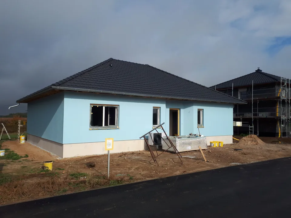 Hellblauer Bungalow mit dunklem Walmdach aus dem Portfolio von Bau Punkt Träder